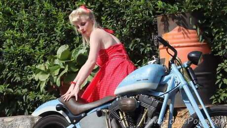 Cute blonde enjoys posing next to a bike